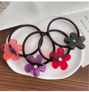 Set mit vier Haargummis aus Harzblumen in Rosa, Lila, Rot und Schwarz auf einer Keramikschale