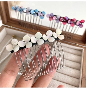 Detail of acetate flower hair comb with pearl finish and crystal centers on metal teeth