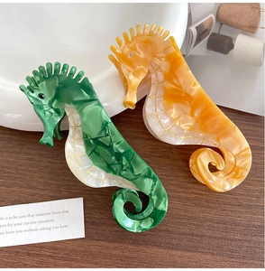 Vue détaillée des pinces à cheveux hippocampe en acétate marbré avec détails dorés et strass