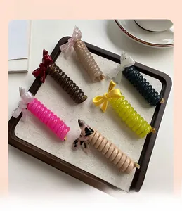 Set of spiral hair ties with acetate bow accents in various colors on a wooden tray