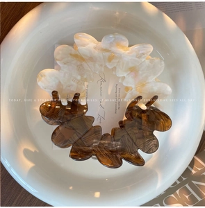 Detailed close-up of premium acetate hair claws with cream marble and amber tortoiseshell patterns