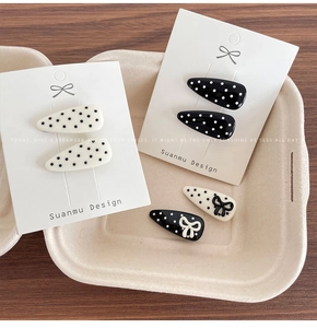 Close-up of polka dot hair clips in black and white on a premium brand display card
