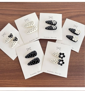 Close-up of black and white polka dot hair clips with floral and bow accents on wood