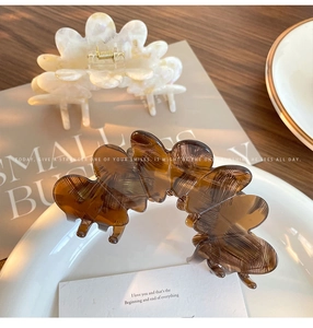 Detailed view of cream and amber acetate flower petal hair claws with gold springs