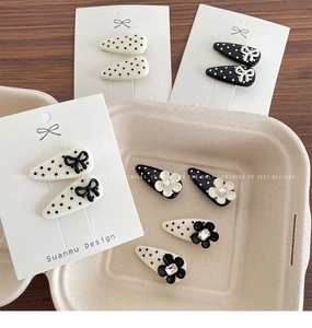 Close-up of black and white polka dot hair clips with bows and flowers on a card