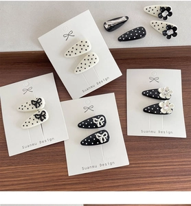 Close-up of minimalist polka dot hair clips with bow and flower on display card