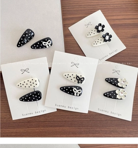 Close-up of polka dot hair clips with 3D bows and floral accents in white packaging