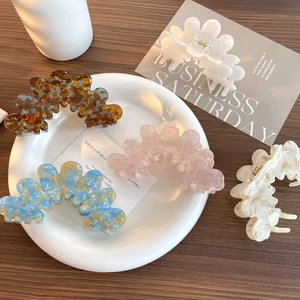 Five assorted marble texture acetate flower petal hair claws displayed on a ceramic tray