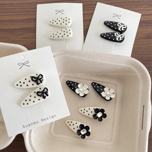 Minimalist polka dot hair clips with bows and flowers on a wooden desk setup