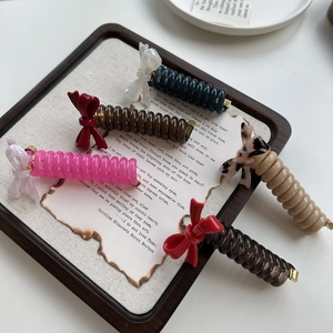 Elegant acetate bow spiral hair ties set in assorted colors on vintage prop