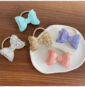 Détail de cinq élastiques à cheveux à nœuds pailletés en bleu, argent, or et violet