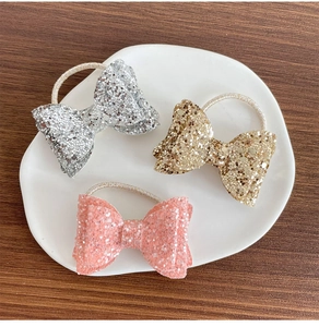Vue détaillée de trois chouchous à paillettes en argent, or et rose sur un plateau