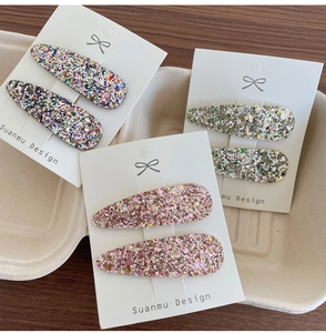 Vue détaillée des barrettes BB pailletées en argent et rose sur carte de marque
