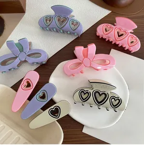 Flache Darstellung von rosa und lila hohlen Herz-Haarklammern und Spangen auf Holztisch