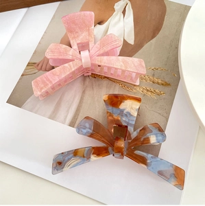 Detail of oversized acetate bow hair claws with marble and tortoiseshell patterns