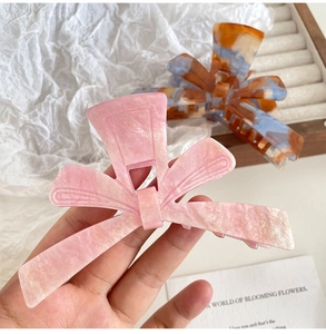 Close-up of pink and blue acetate bow hair claws with elegant marble textures