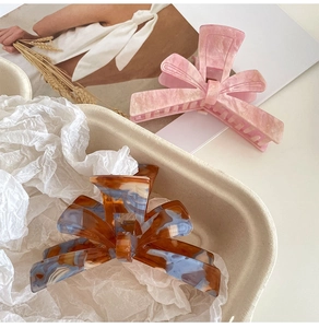 Close-up of marble pink and tortoise blue acetate bow hair claws on a minimalist tray