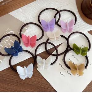 Flat lay of eight colorful acetate butterfly hair ties on a rustic wooden background