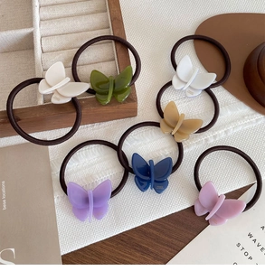 Detail of 6-color acetate butterfly hair ties with elastic bands in a cozy setting