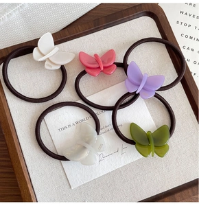 Macro detail of acetate butterfly hair ties in a wooden tray with handmade engraving