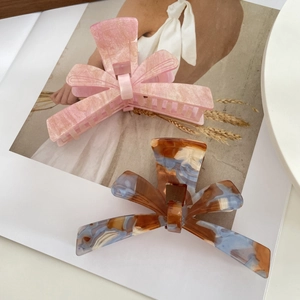 Elegant acetate bow hair claws with marble and amber patterns in a premium gift-ready setting