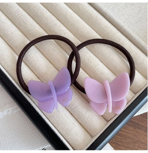 Detailed macro view of handmade acetate butterfly hair ties in lilac and pastel pink colors