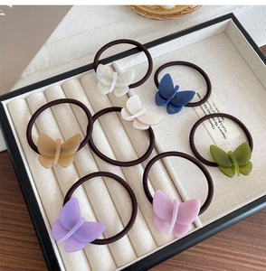 Close-up of 7 colors butterfly acetate elastic hair bands on a cream jewelry display tray