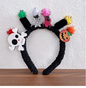 Detail of Halloween headband with plush spiders, skulls, and colorful pom-poms on wood background