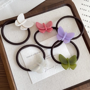 Five pieces of acetate butterfly hair ties in colorful minimalist style on wooden tray