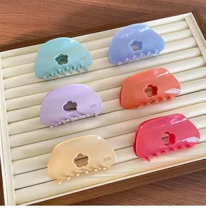 Détail des pinces à cheveux à fleurs évidées en couleurs macaron sur un plateau