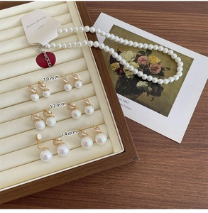 Detail view of pearl necklace and golden bow earrings on a jewelry display tray