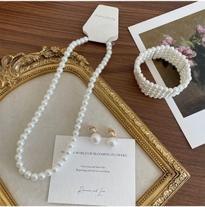 Three-piece elegant pearl jewelry set featuring a necklace, bracelet, and drop earrings