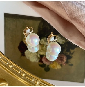 Close-up of elegant iridescent pearl earrings with gold base on a vintage mirror surface