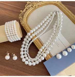 Elegant multi-layer pearl jewelry set including necklace, bracelet and earrings on wood table