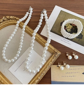Elegant pearl jewelry set with necklace and bracelet on vintage wood background
