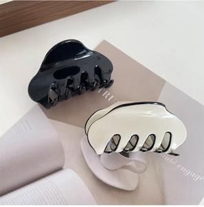 French style acetate hair claw clips in black and cream white on a ceramic tray