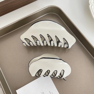 Classic French cream white acetate hair claw clips with black trim on vintage tray