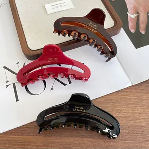 Three acetate hair claws in dark brown, burgundy, and black with a glossy finish