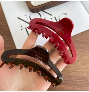 Detailed view of large dark red and tortoiseshell acetate hair claws with gold lettering