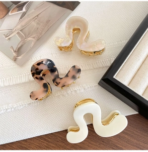 Detail view of acetate shark hair clips in pearl pink, tortoiseshell and milk white color