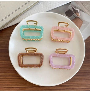 Set of four square acetate hair claws in pastel marble colors on a ceramic tray