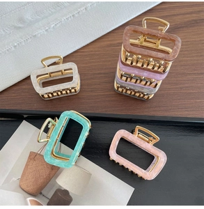 Macro detail of elegant square acetate hair claws with marble texture and gold metal spring