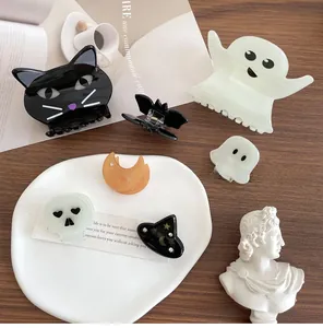Flat lay of Halloween hair clips featuring black cat, ghost, and bat on a wooden table