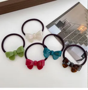 Close-up of five colorful acetate bow hair ties in cream, green, red and tortoiseshell