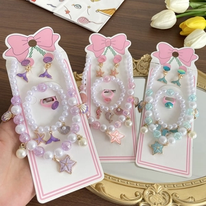 Ocean theme kids jewelry set with pearls, shells, and starfish on a wood background