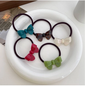 Detail of five colorful acetate bow hair ties in a ceramic plate with France Handmade text