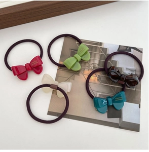 Detail of 5-piece set of colorful acetate bow hair ties in red, green and beige