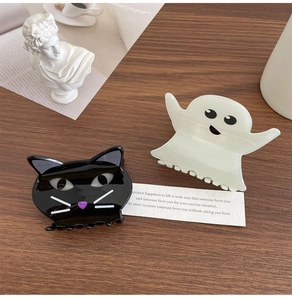 Detail of Halloween acetate cat and ghost hair clips on a rustic wooden table