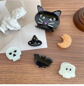 Flat lay of Halloween hair clips featuring cat, ghost, bat and skull on a wooden desk