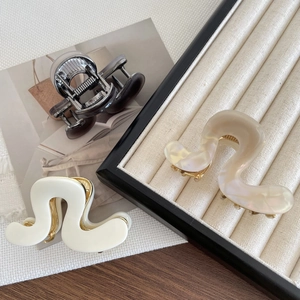 Minimalist acetate hair claw clips set in wavy designs and pearlescent finishes